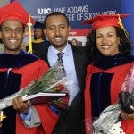 Two masters students celebrate with a friend