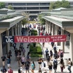 students walking on campus under a welcome banner