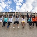 Young women sitting in a line on a wall