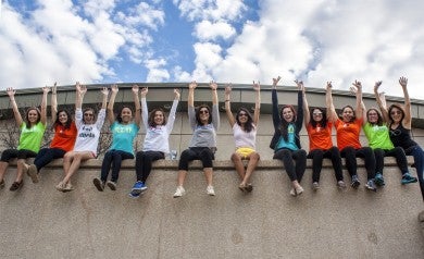 Young women sitting in a line on a wall