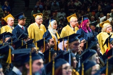 men and women standing in line wearing graduation caps and gowns