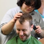 Woman shaves the head of a man