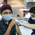 Srinivas Gollapudi smiles under his mask as he receives the COVID-19 vaccine in the Credit Union 1 Arena on Monday, Feb. 1, 2021, at the University of Illinois Chicago. (Joshua Clark/University of Illinois Chicago)