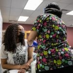 Sania White gets her first shot of the Moderna COVID-19 vaccine at the Mile Square Health Center in Englewood.