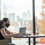 Masked student working on laptop