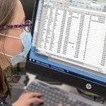 Woman wearing a mask looking at computer screen