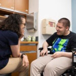 A doctor talks with a patient in a wheelchair