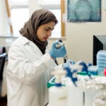 A scientist works in their lab with a syringe in their hand.