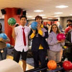 Students hold up bowling balls at Millennium Lanes