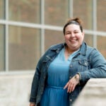 a woman in a jean jacket and blue dress outside