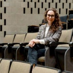 A woman sits in an auditorium seat