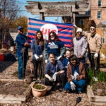 a group of UIC students and other volunteers pose for a photo in a community garden