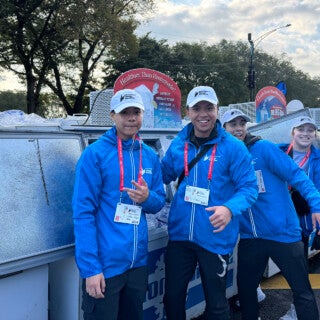 UIC students in kinesiology and exercise psychology volunteered at the Oct. 13 Chicago Marathon, to offer runners encouragement and medical help. (Photo: Michele Kerulis and Meredith Wekesser) two student volunteers in blue jackets at the Chicago Marathon