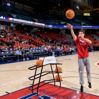 On Feb. 1, UIC college deans and students participated in the Dean's Challenge, a friendly competition between the university's colleges. The contest will conclude during the Feb. 23 UIC women's basketball game against Evansville. (Photo: UIC Athletics) a student shoots a basketball at Credit Union 1 Arena
